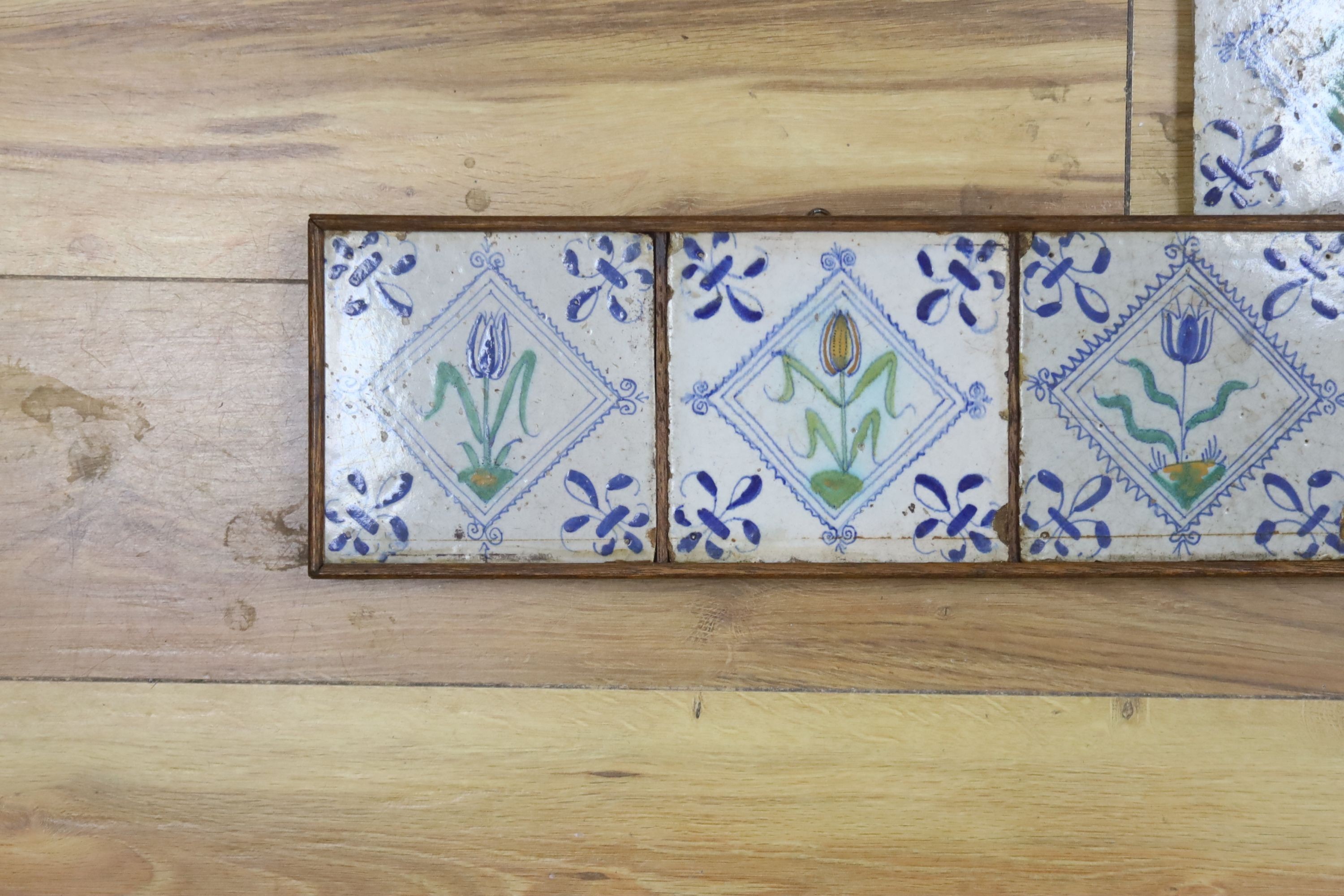 Seven 17th century Dutch Delft tiles, polychrome-decorated with tulips and having fleur-de-lys corners (framed 95cm)